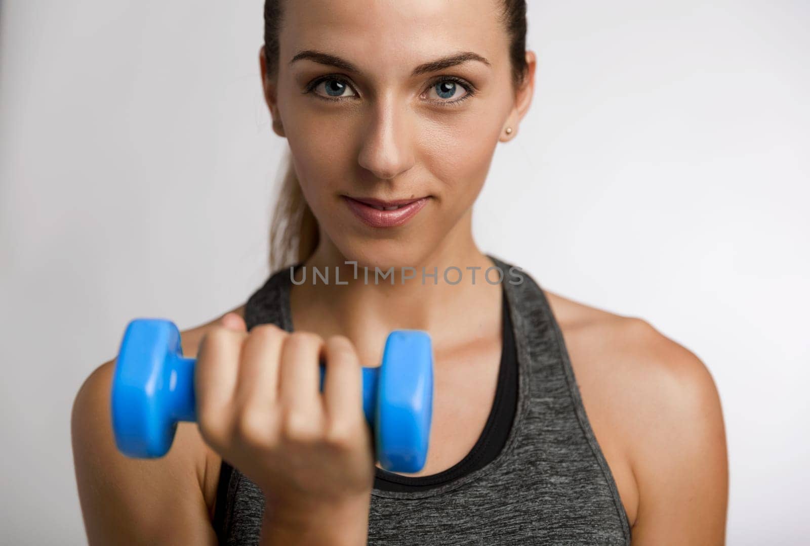 Young fitness woman making exercises with dumbbells