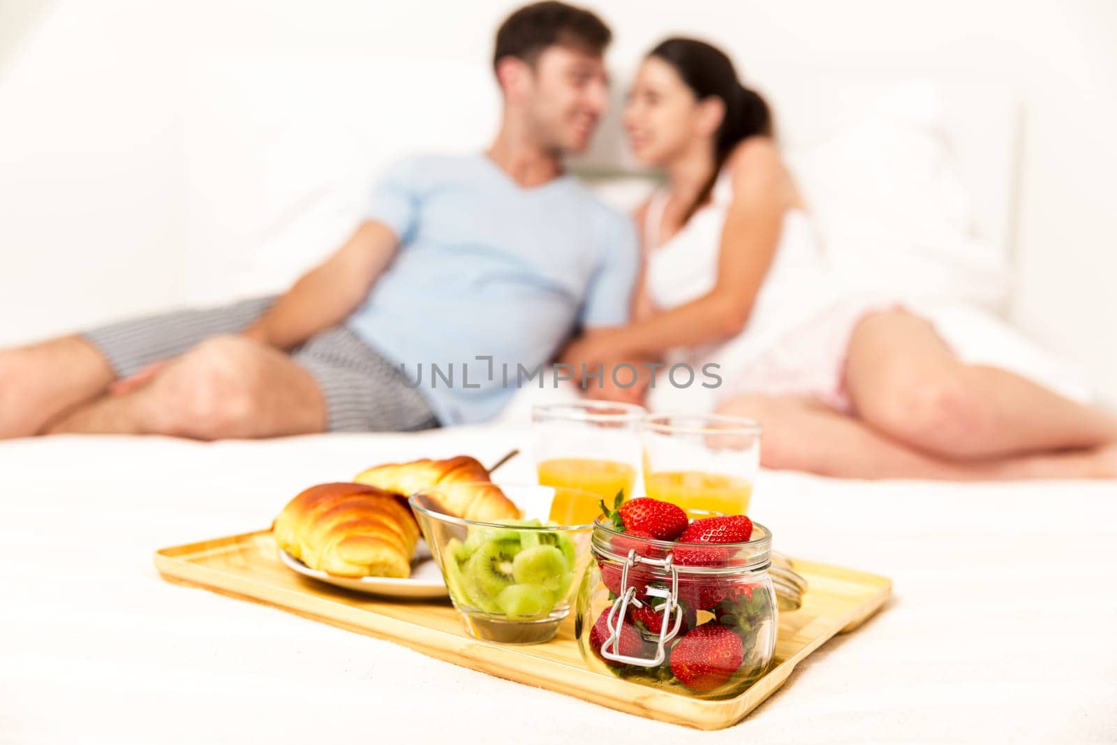 Young couple lying on the bed with breakfast on bed