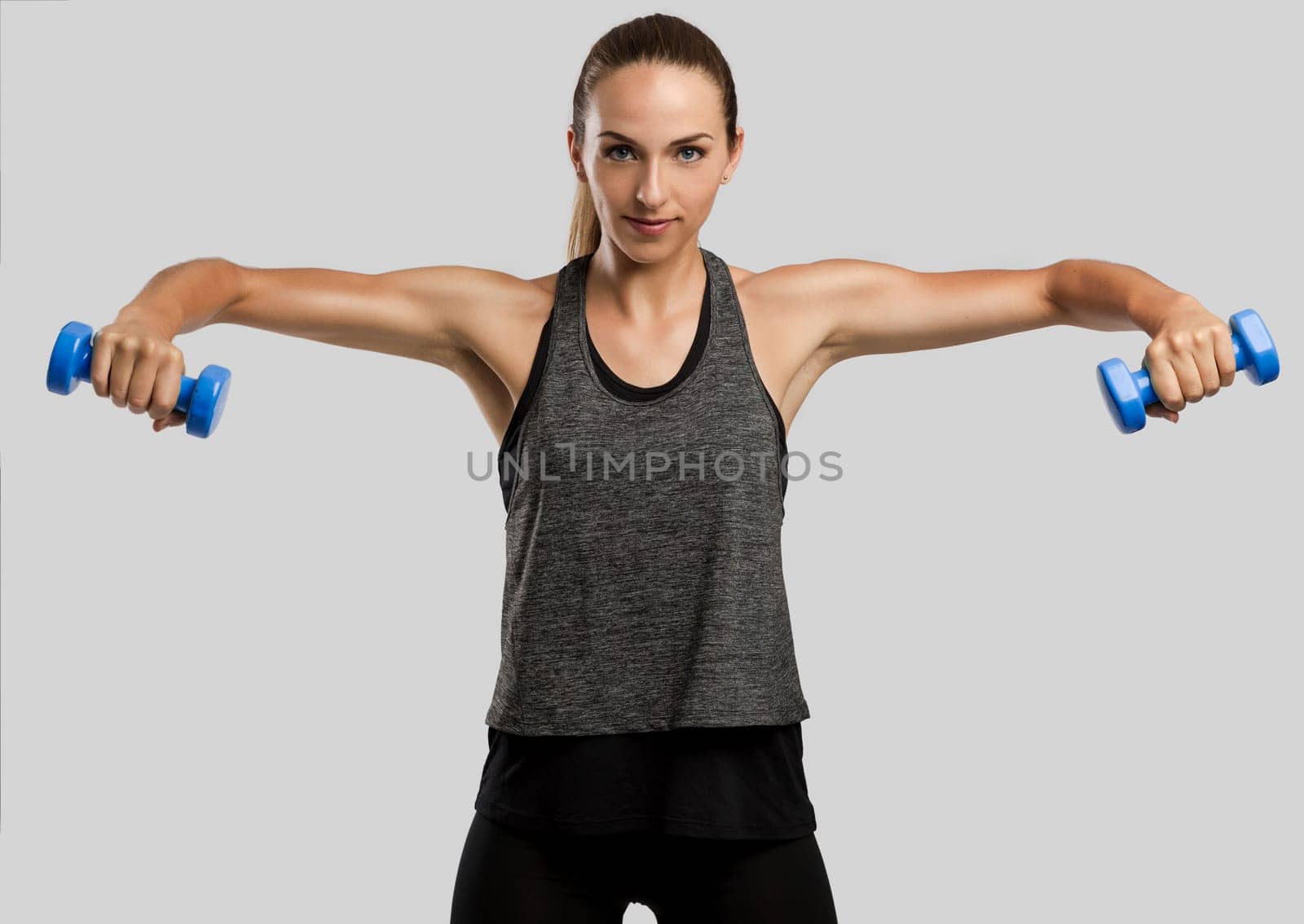 Young fitness woman making exercises with dumbbells