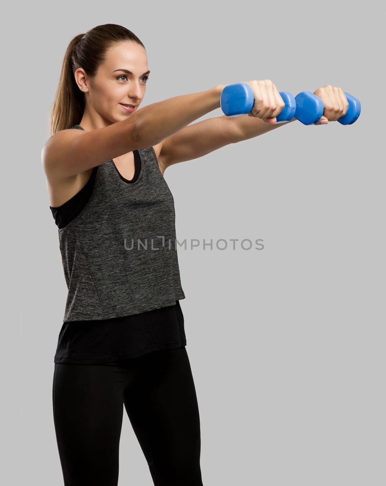 Young fitness woman making exercises with dumbbells
