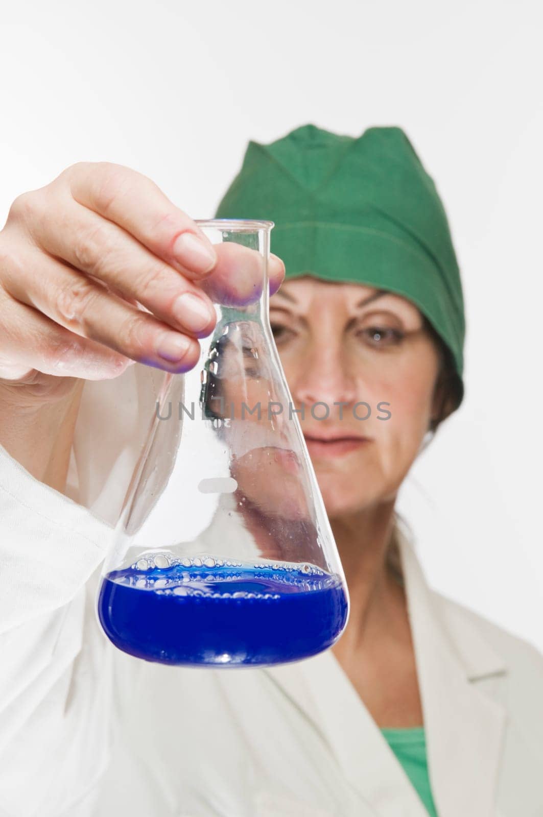 Laboratory technician holds a glass flask with blue liquid and controlling gaze.