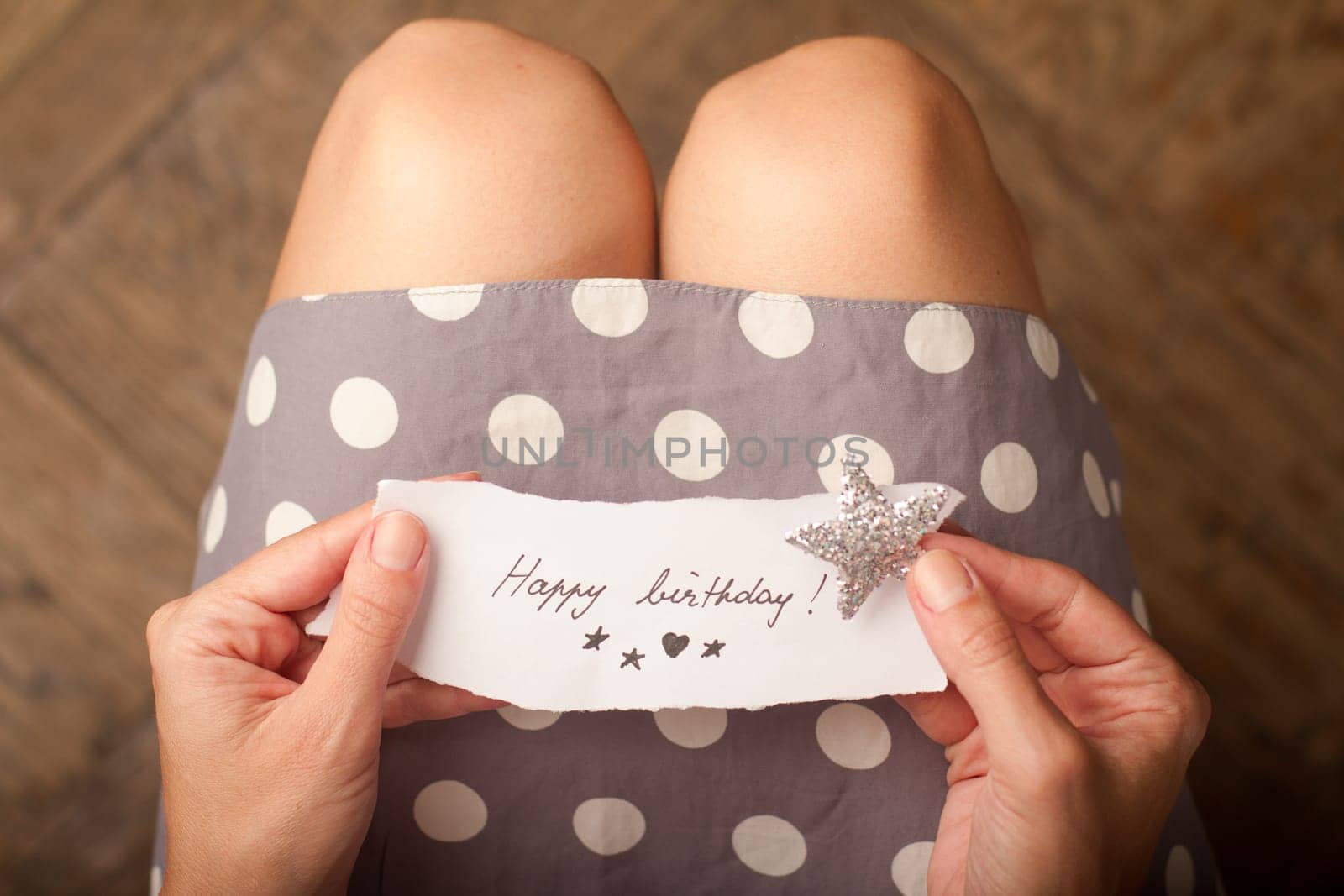 Hand holding a note of paper with the message happy birthday on it