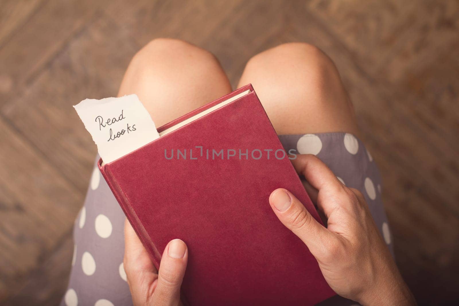Hand holding a book with note of paper with the message read books on it