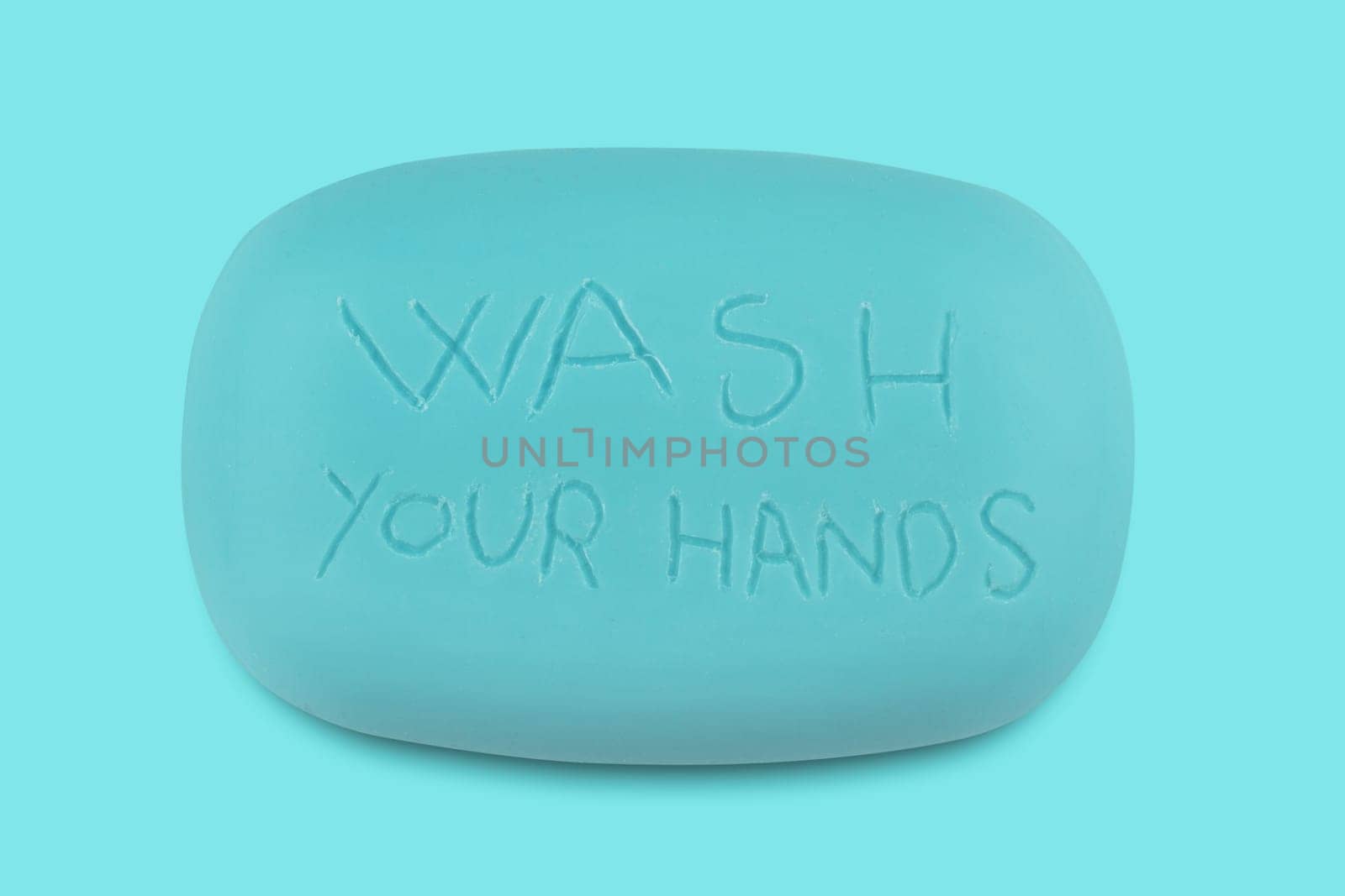 Top view of a blue soap bar with the words wash your hands scratched on it