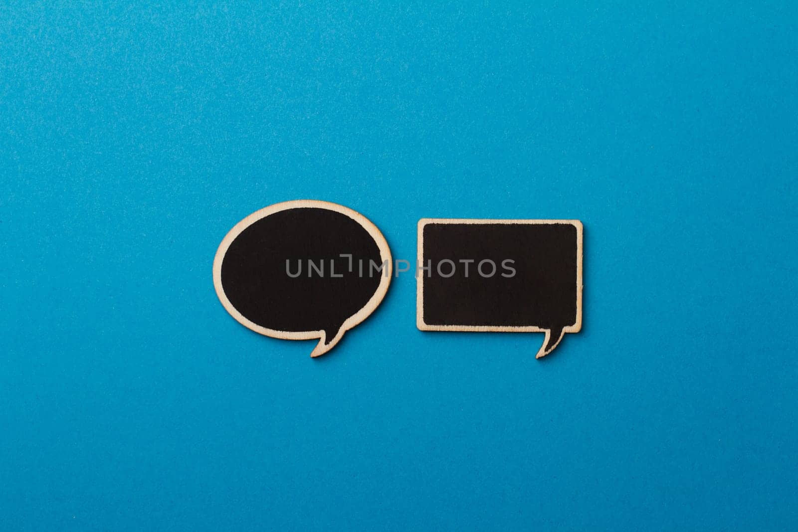 horizontal top view of charcoal wooden speech bubbles with different shapes on blue background