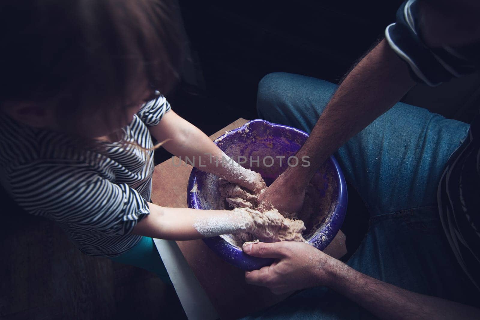 Top view of father and daughter working the dough of a bread together