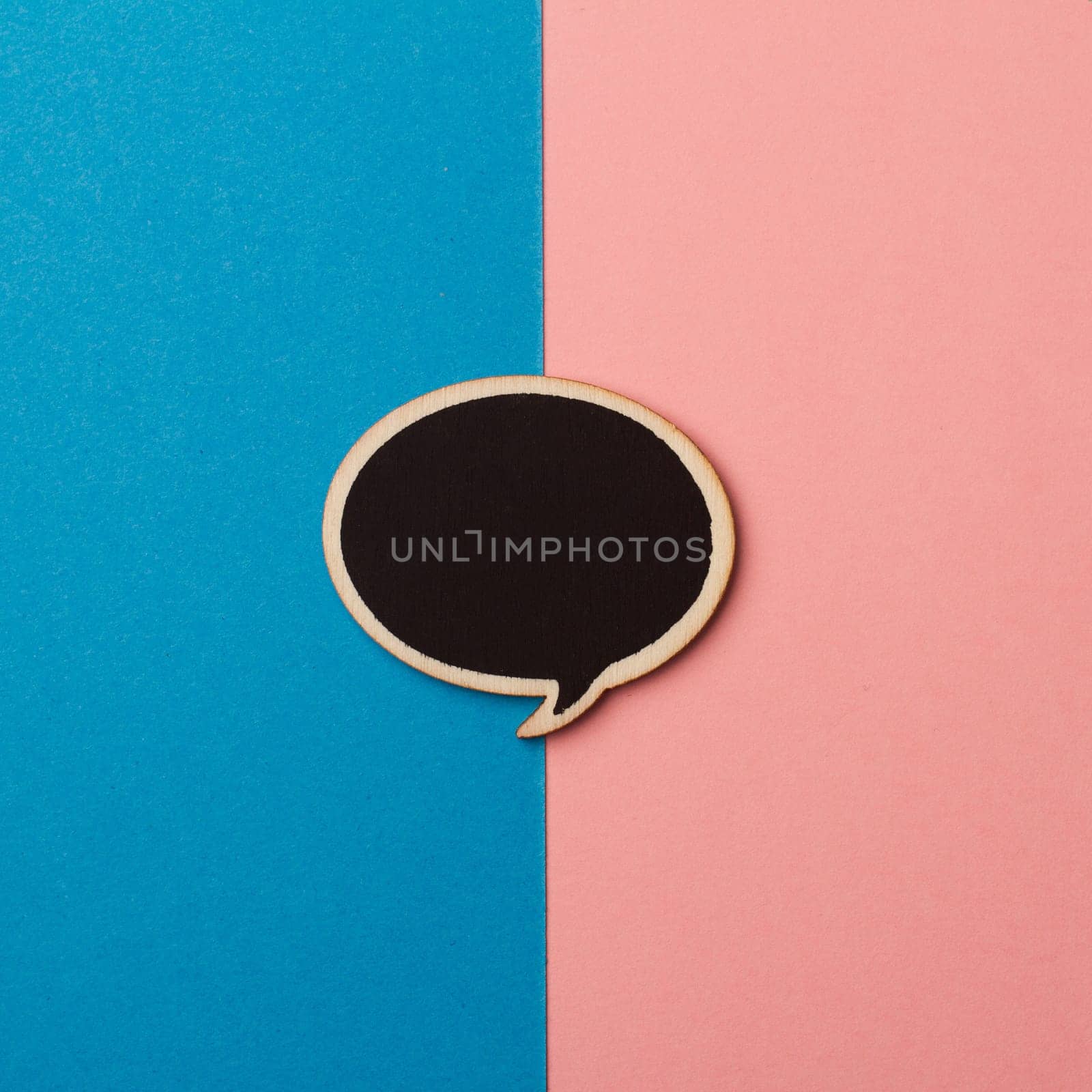 Top view of round empty chalkboard wooden speech bubble on pink and blue background