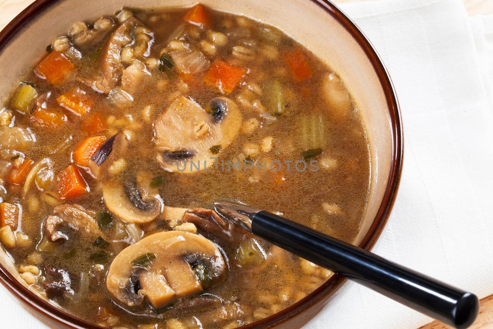 Bowl of homemade mushroom and barley soup with spoon in it ready to eat