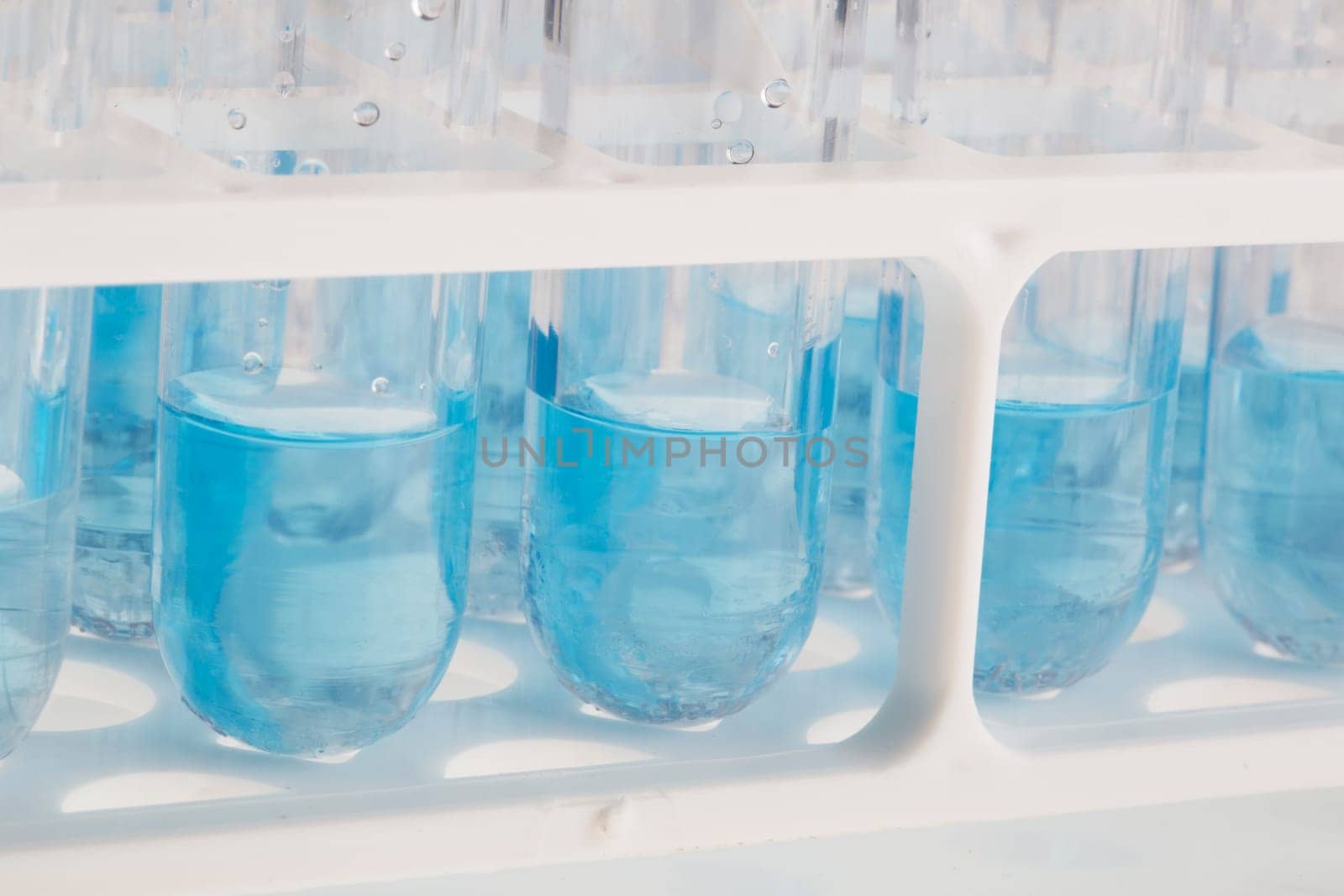 Close up of test tubes in rack with blue liquid.