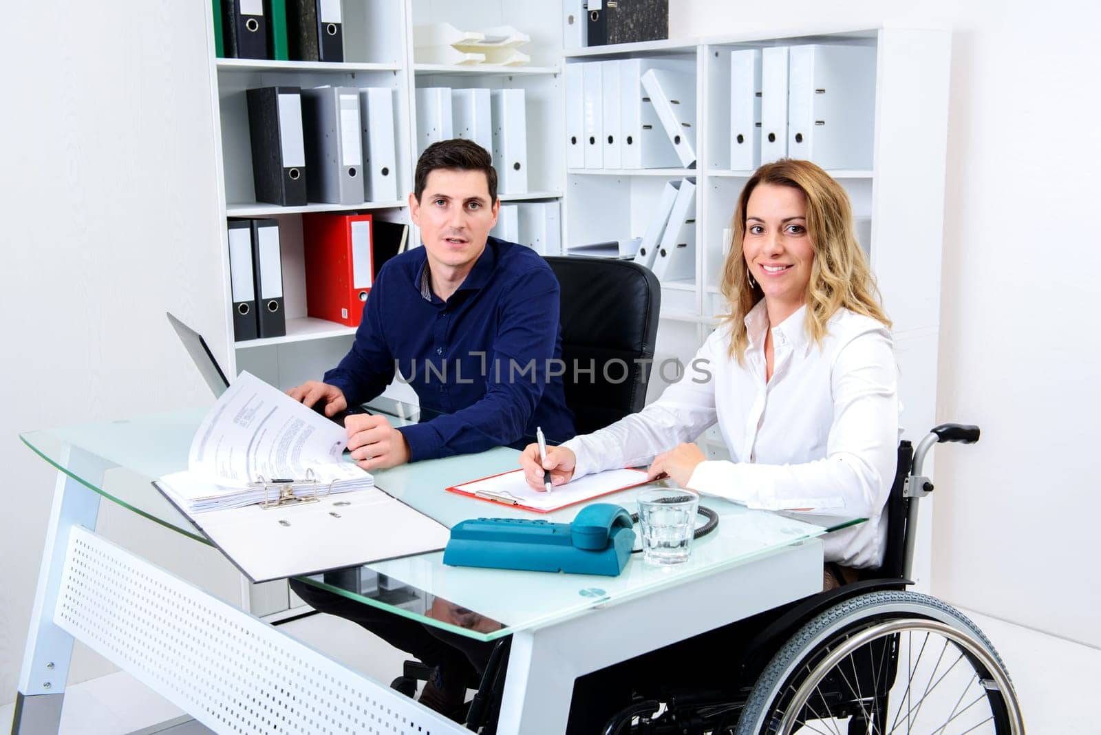 disabled businesswoman in wheelchair and her colleague in the office