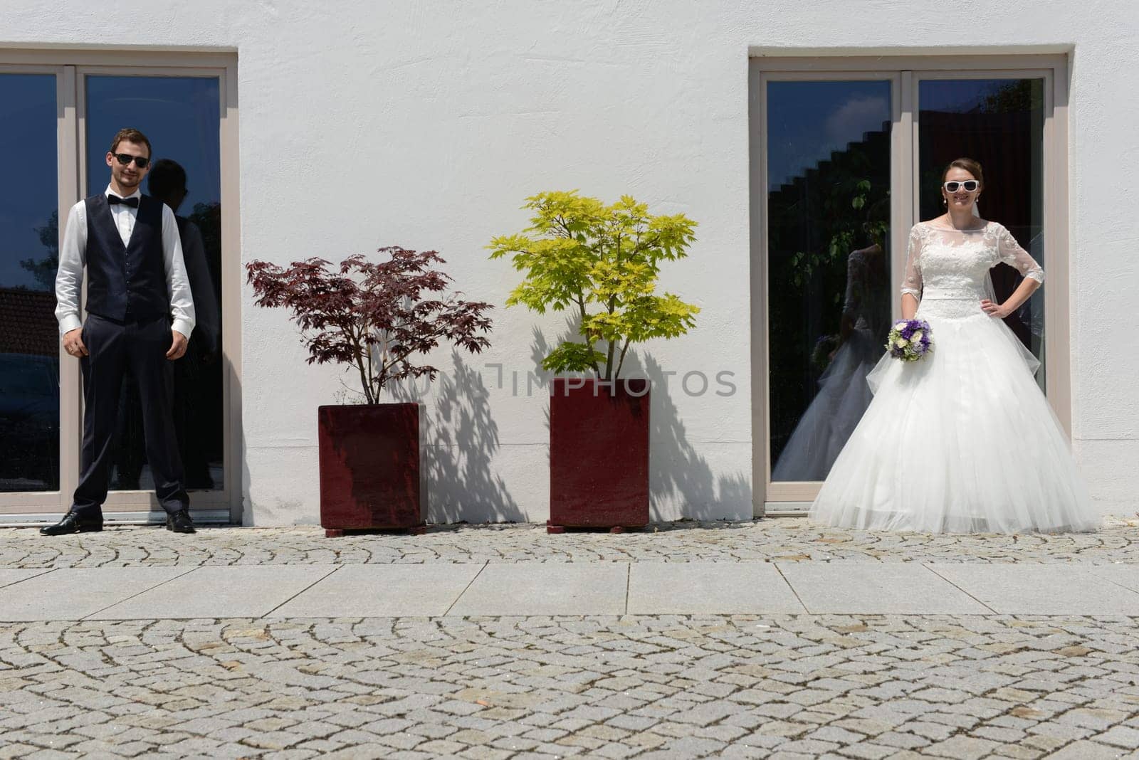 Happy young bridal couple with sunglasses in front of an old house