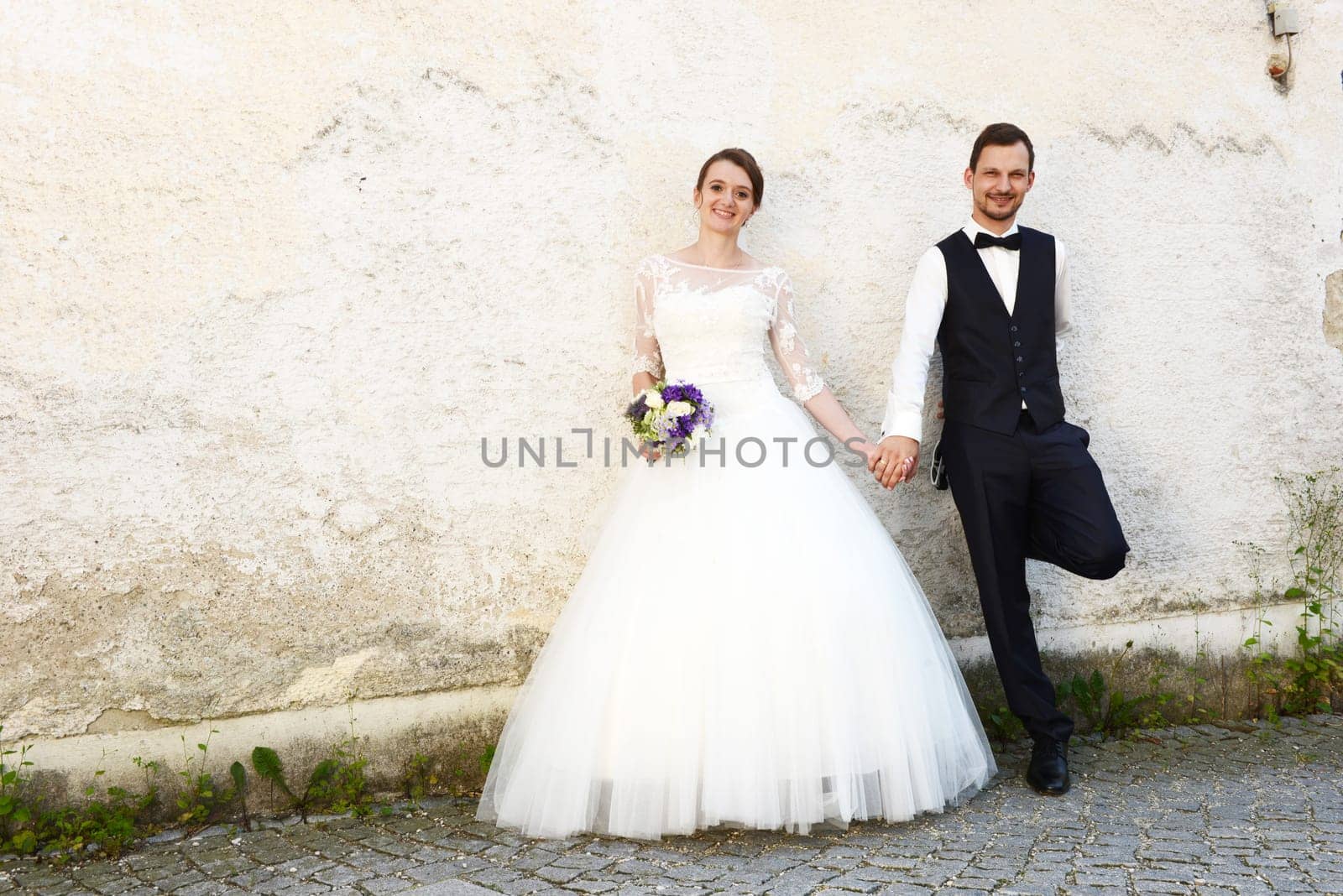 Happy young bridal couple in front of an old house wall