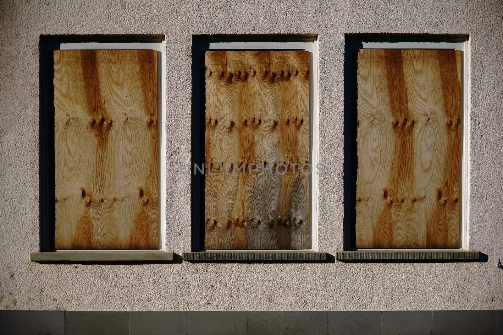 A dilapidated building with nailed windows and a yellowed façade.