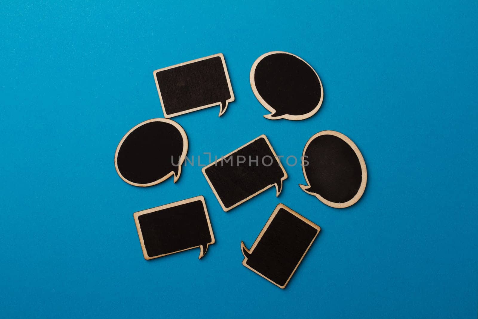 Horizontal top view of many chalkboard wooden speech bubbles on light blue background, team work concept
