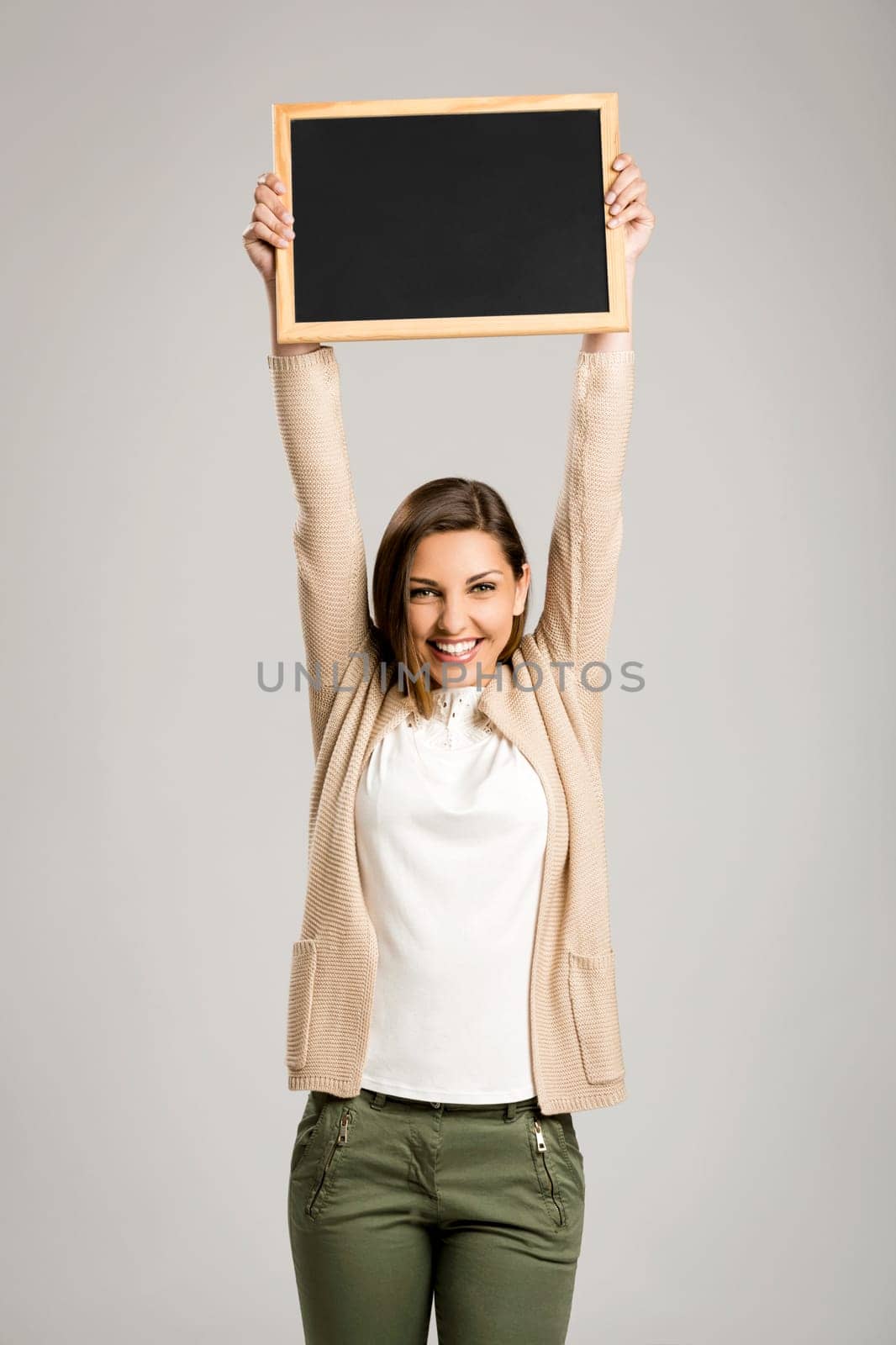 Beautiful and happy woman holding and showing a chalkboard very high
