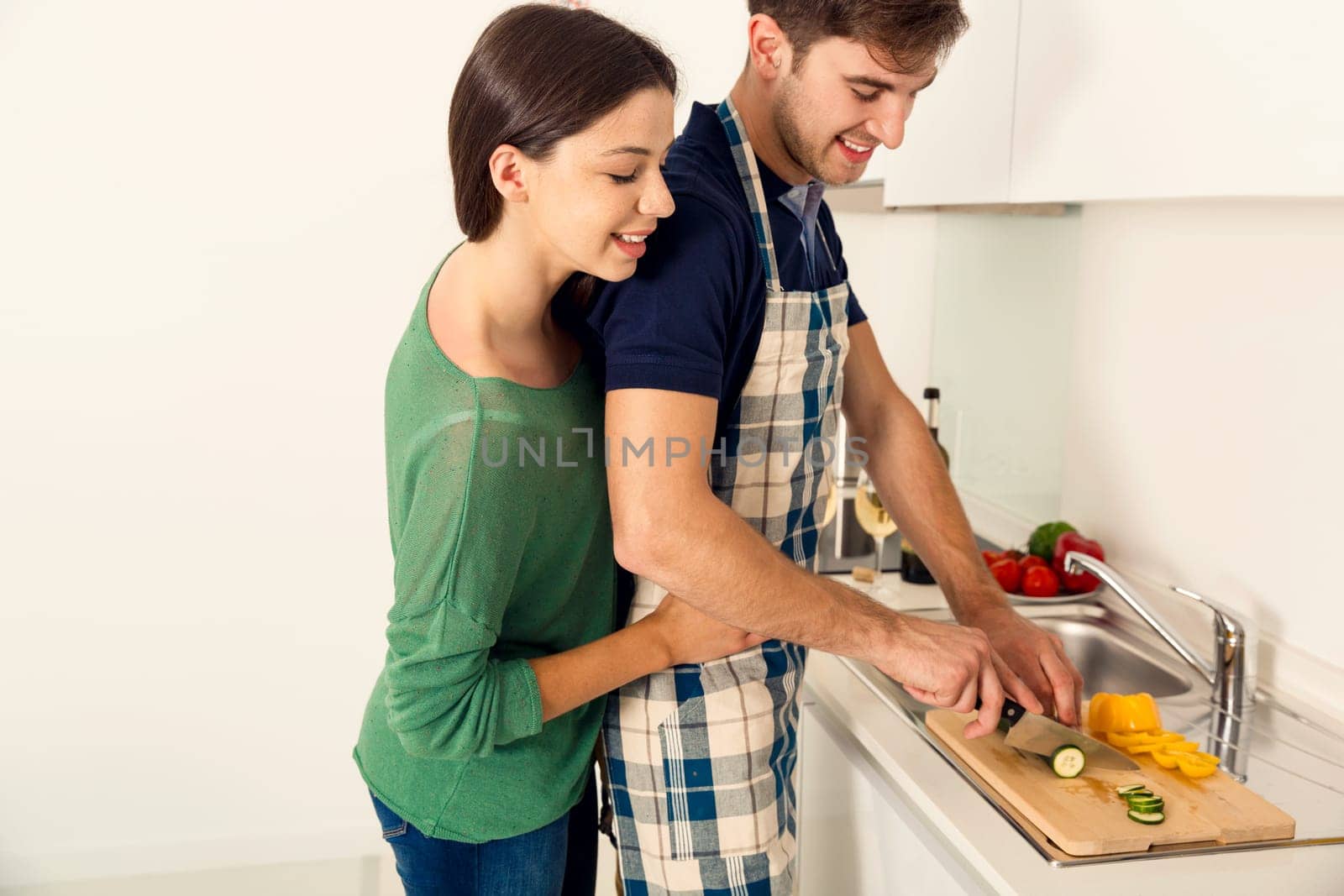 Young couple on the kitchen follow a recipe by tablet and cooking