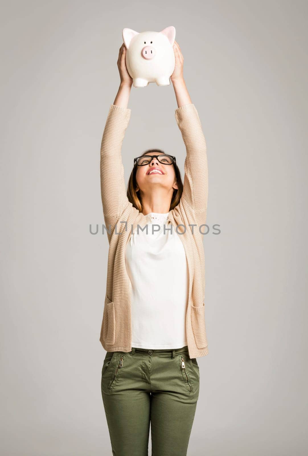 Beautiful and happy woman holding a piggy bank and making thumb up