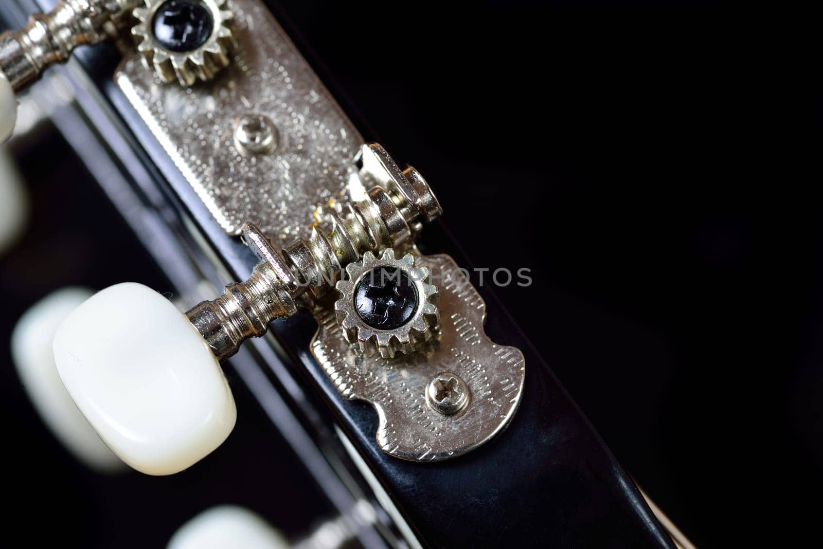 Close-up of a guitar tuning machine head with pegs
