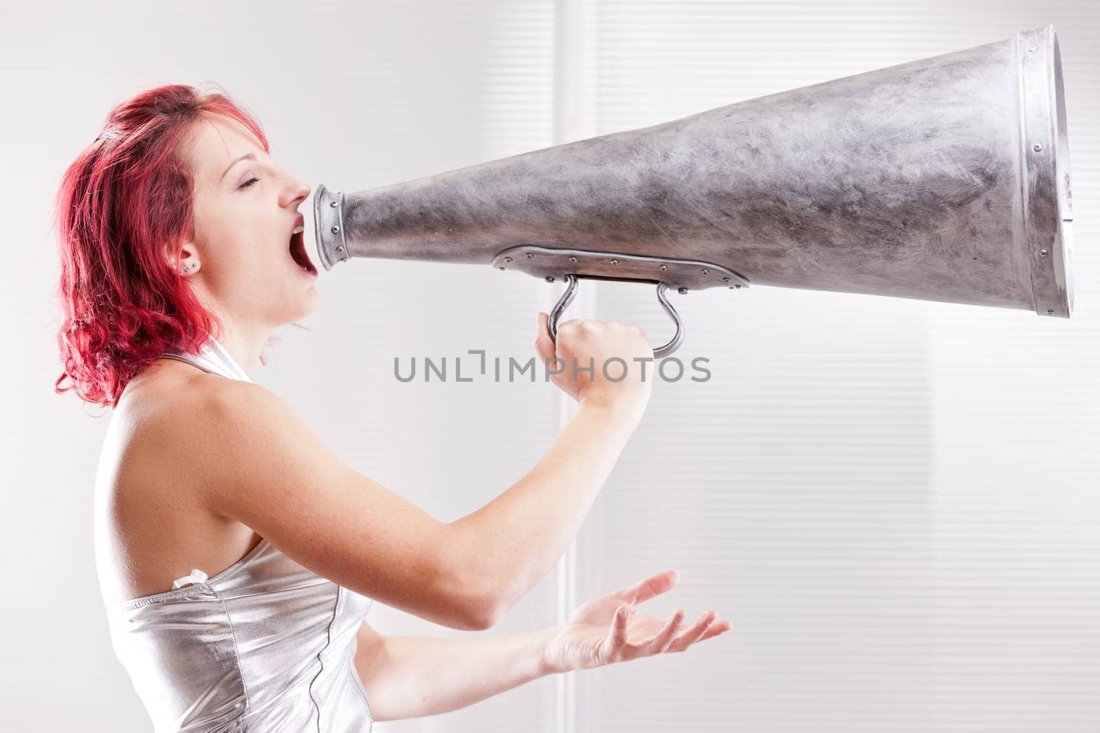 red haired vintage space costume girl shouting in a vintage megaphone