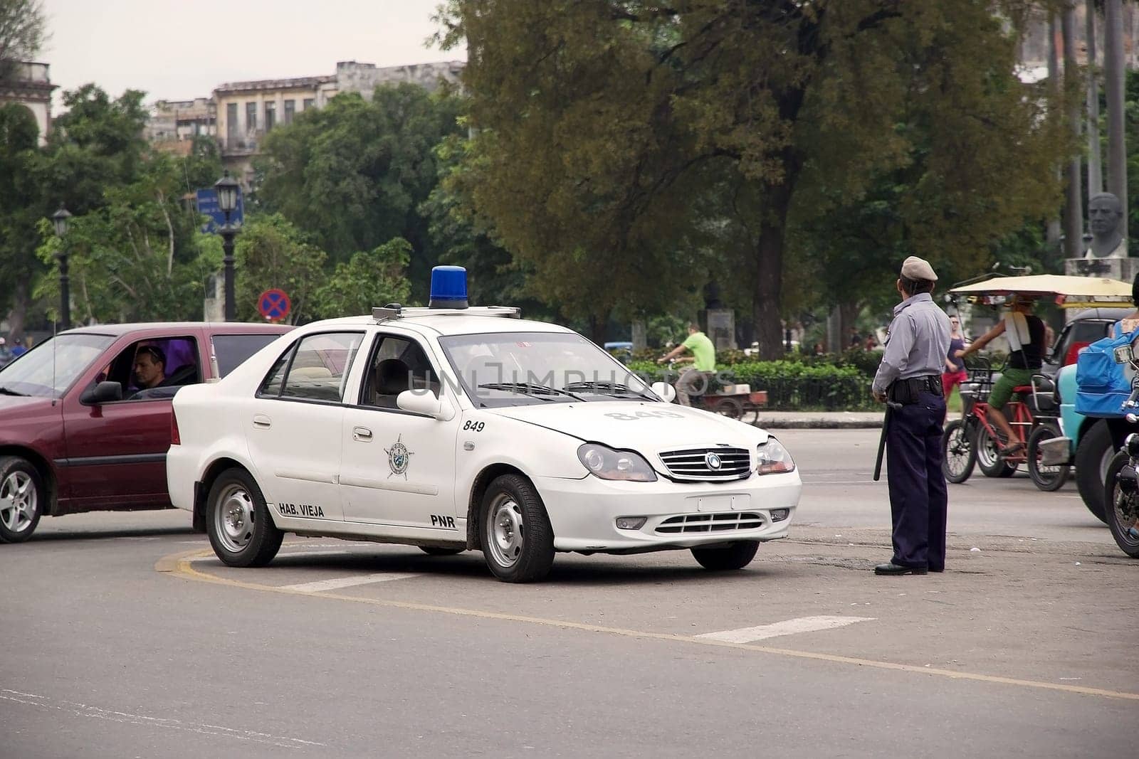 policeman with police car is control the situation along the Paseo de Prado at the Old Havana. PNR, Policia National Revolucionaria is under the administration of the Cuban Ministry of the Interior