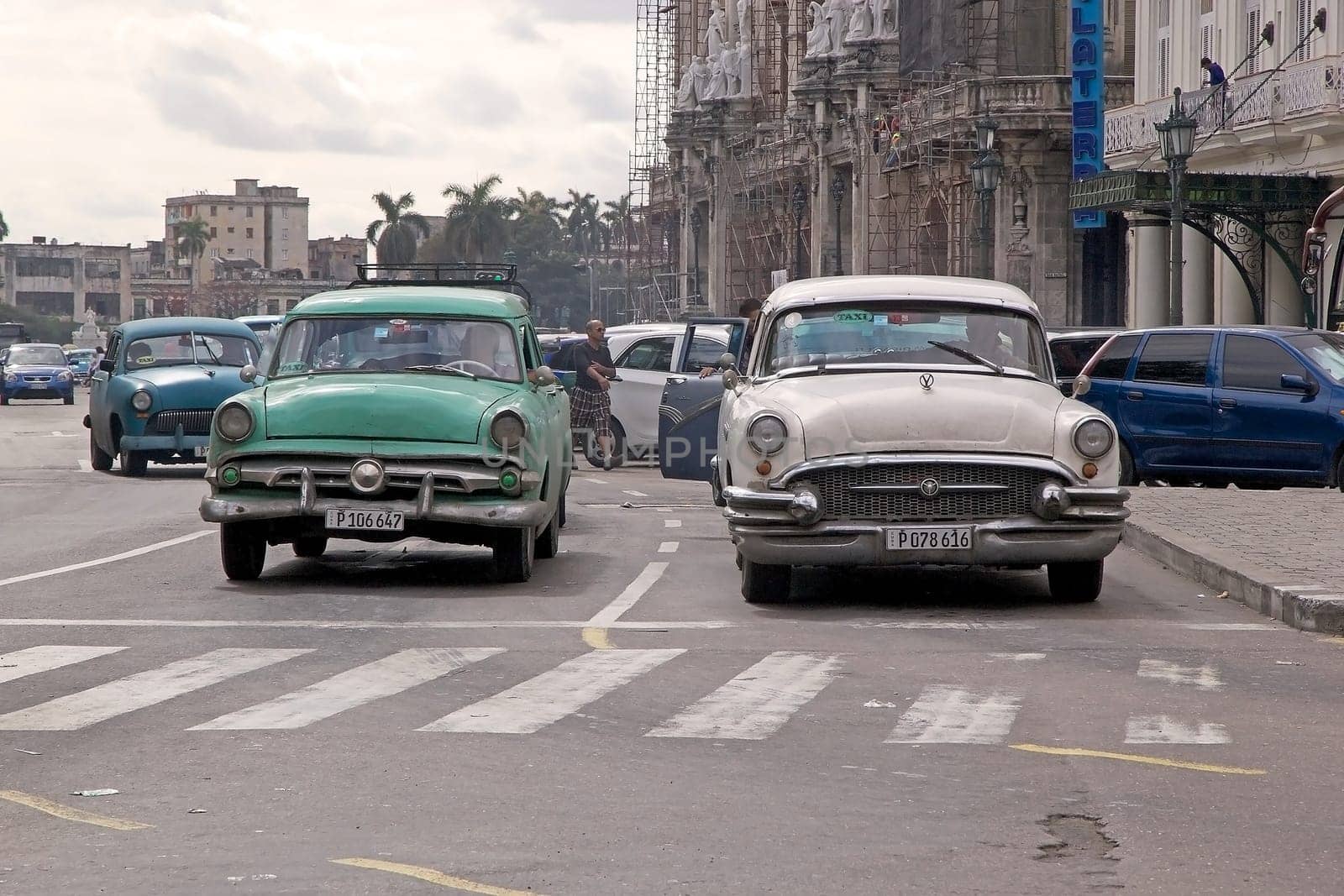 Cuban men are driving a old classic american cars along the street in Havana, Cuba