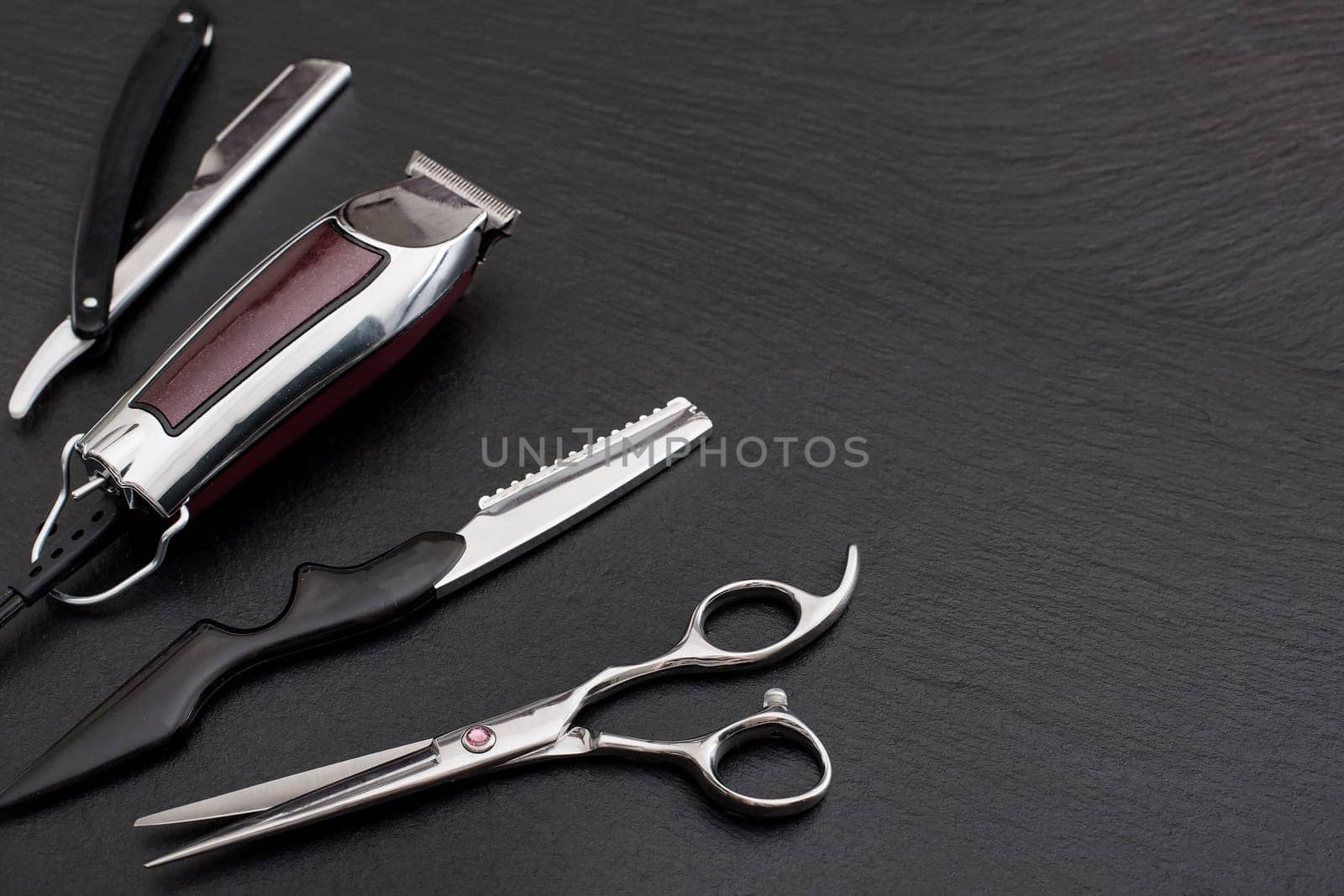 Barber shop equipment on Black background with place for text.  Professional hairdressing tools. Comb, scissor, clippers and hair trimmer isolated.
