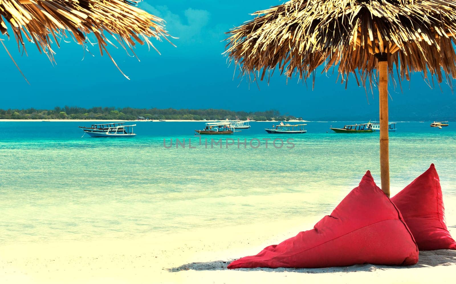 Straw umbrellas and bean bag at the seashore.