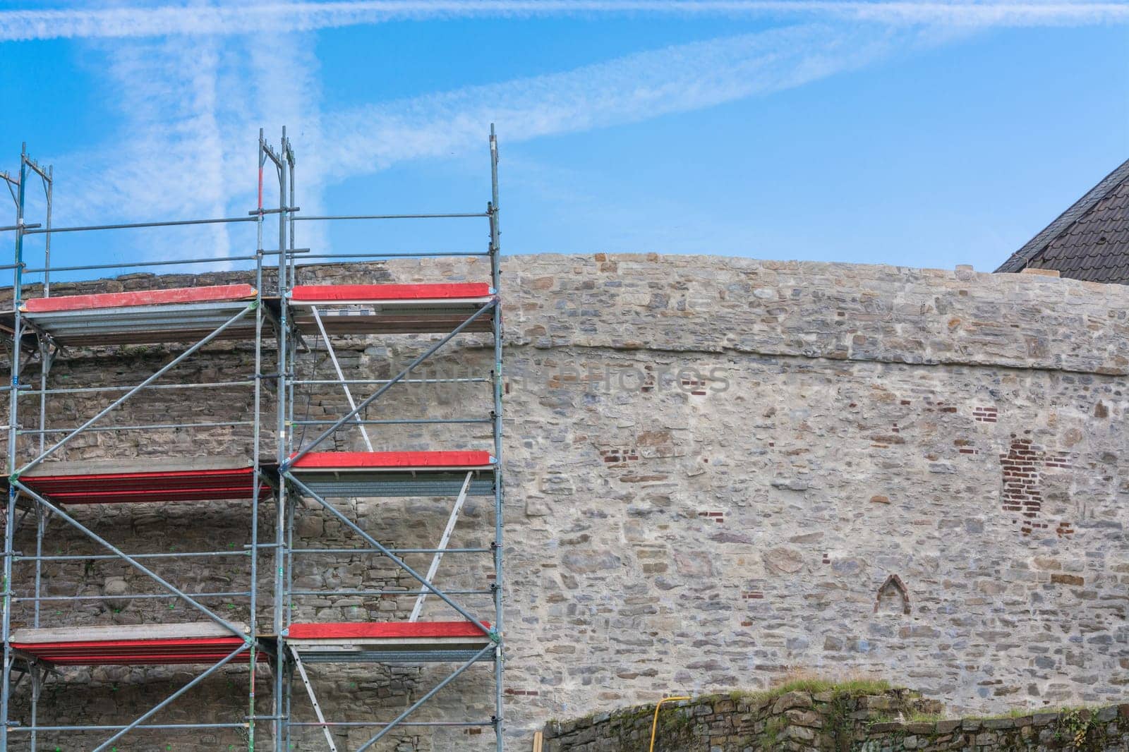 Old castle wall with scaffolding in front of blue sky..