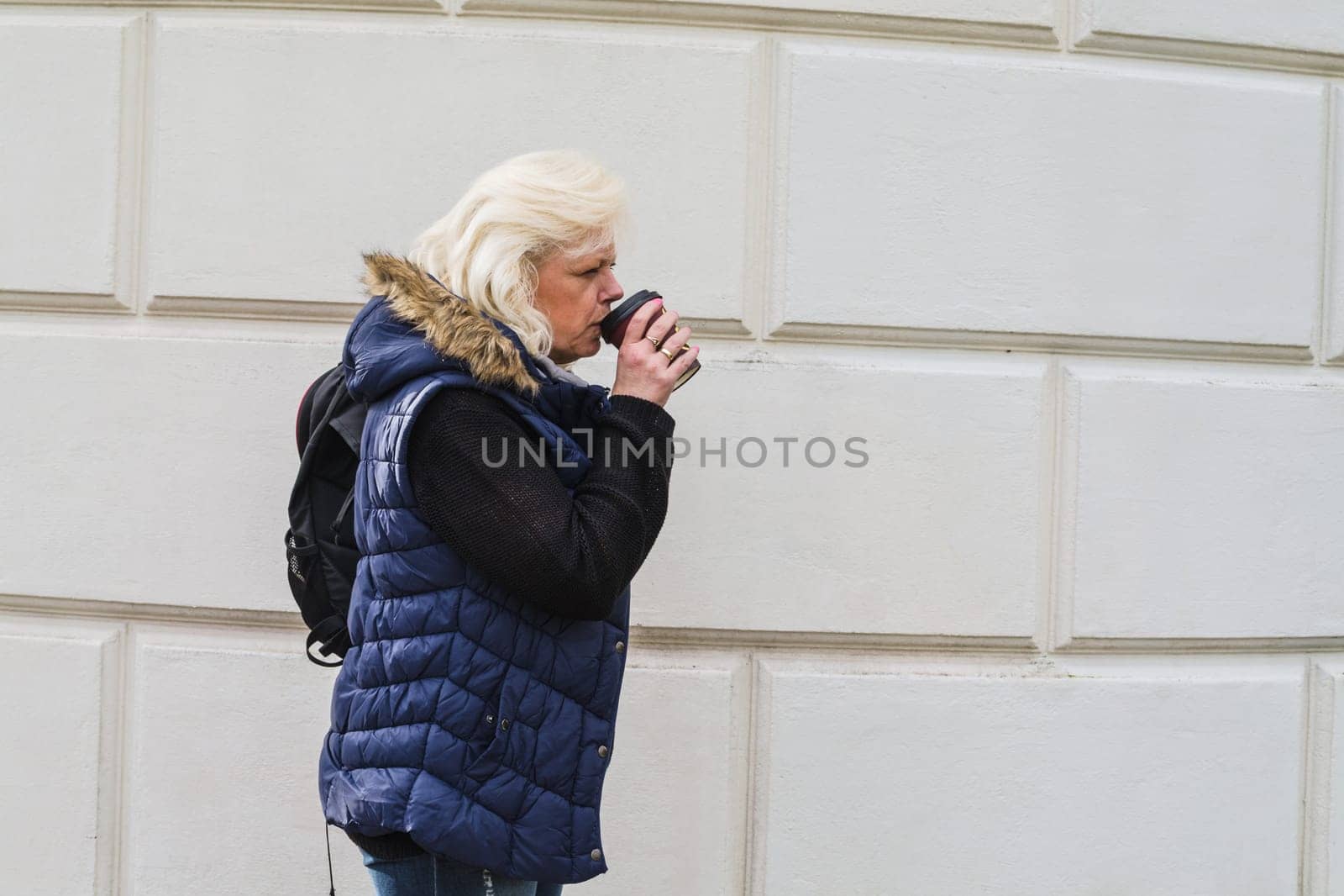 Side portrait of a blonde woman with a coffee to go..
