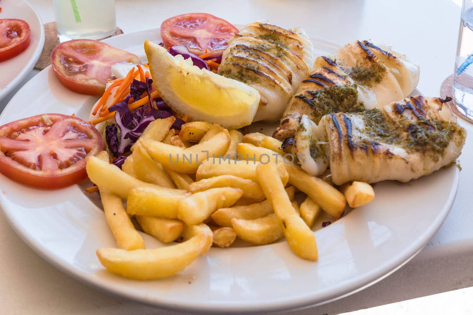 Gegrillten Oktopus. Gegrillter Tintenfisch serviert mit Pommes frittes und Zitronen und Salat..