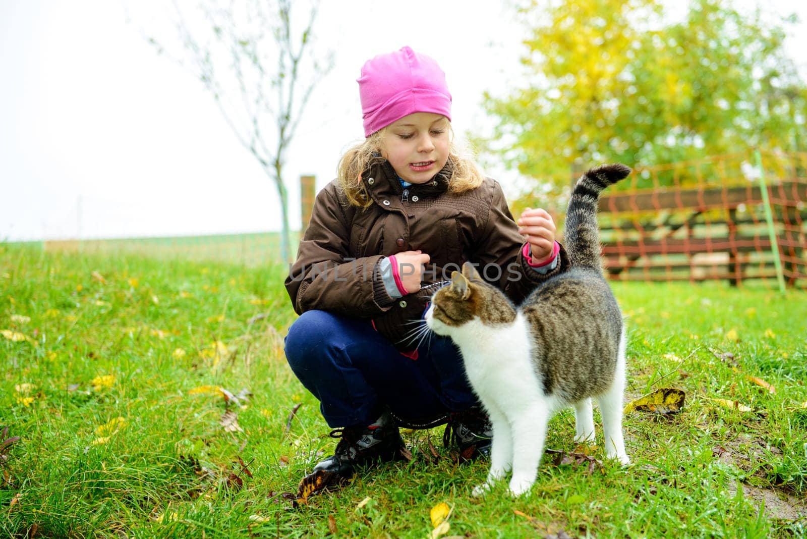 little girl playing with cat in front of nature background
