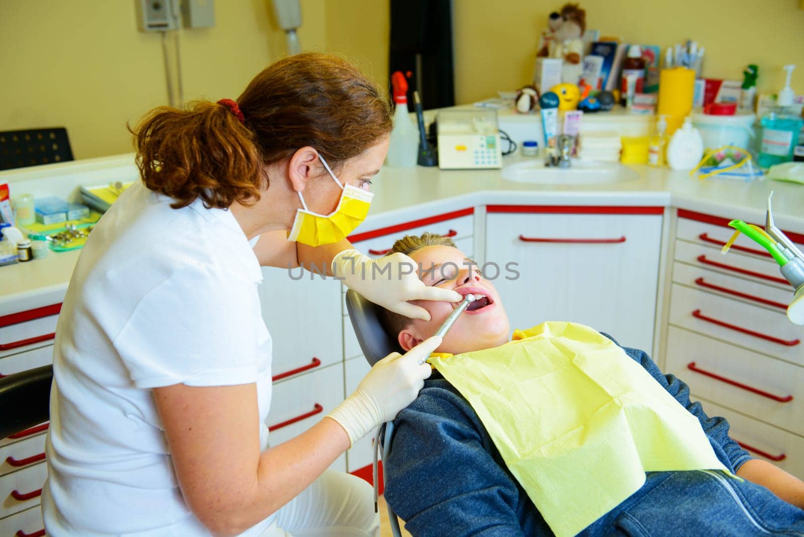 teenager is treated by female dentist in dental surgery