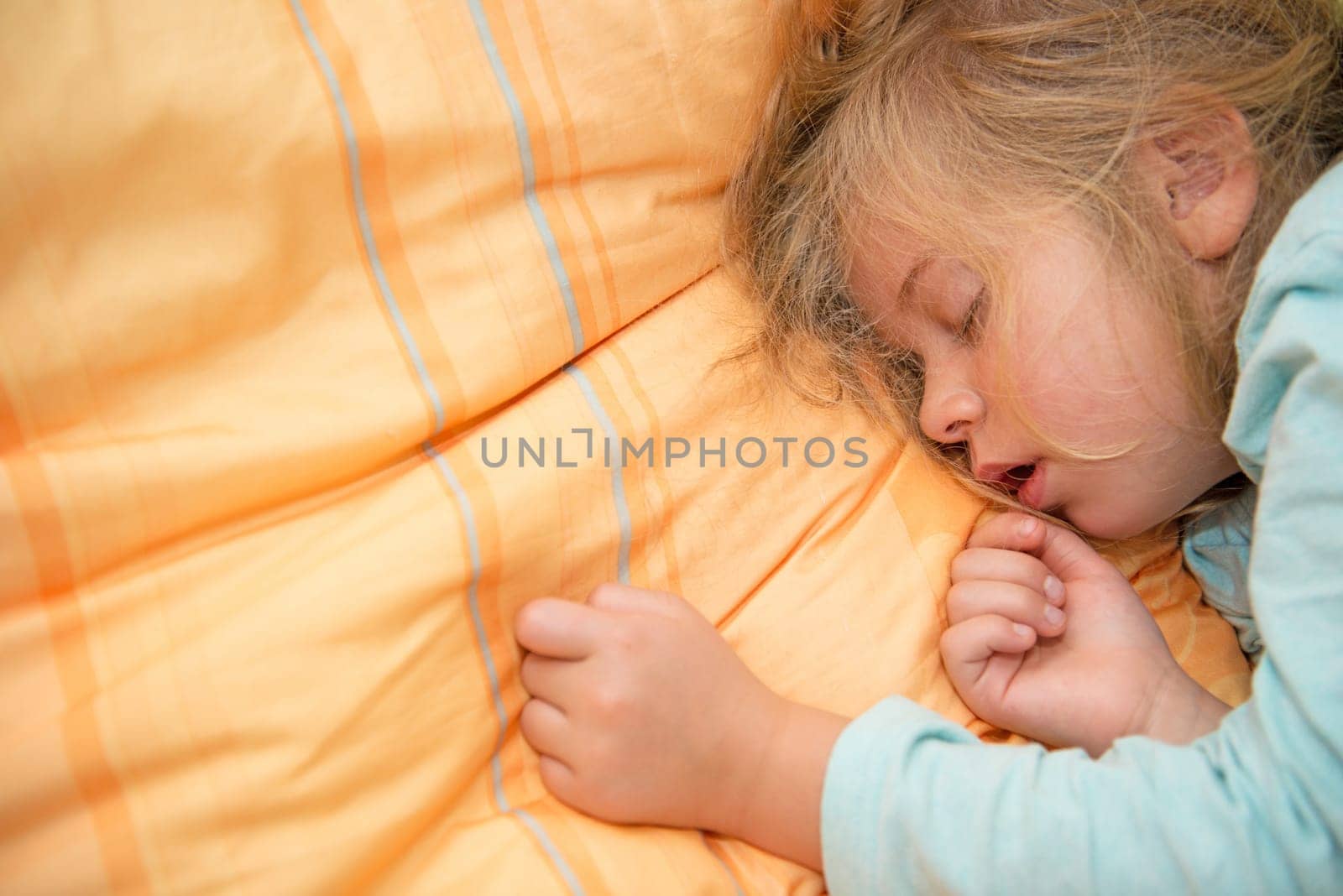 little girl is sleeping on orange pillow