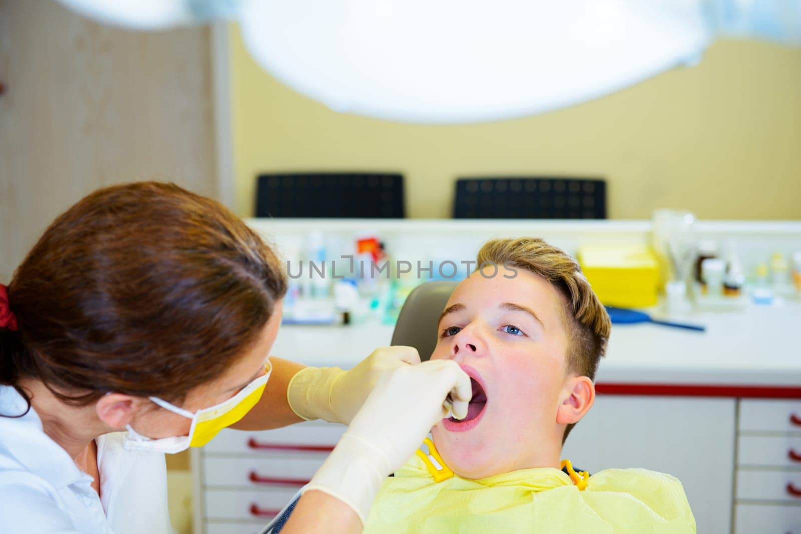 teenager is treated by female dentist in dental surgery