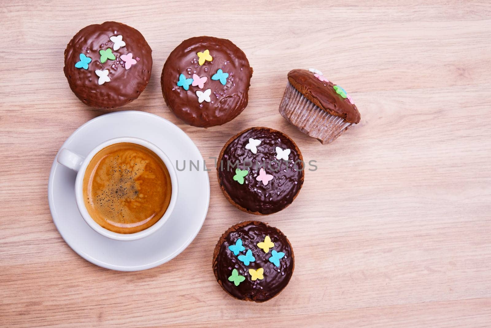 chocolate muffins with cup of coffee on wooden ground