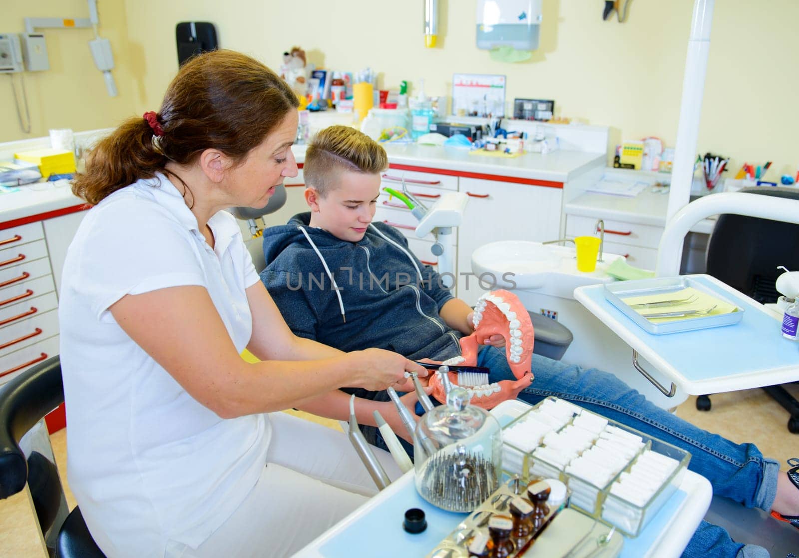 teenager is treated by female dentist in dental surgery