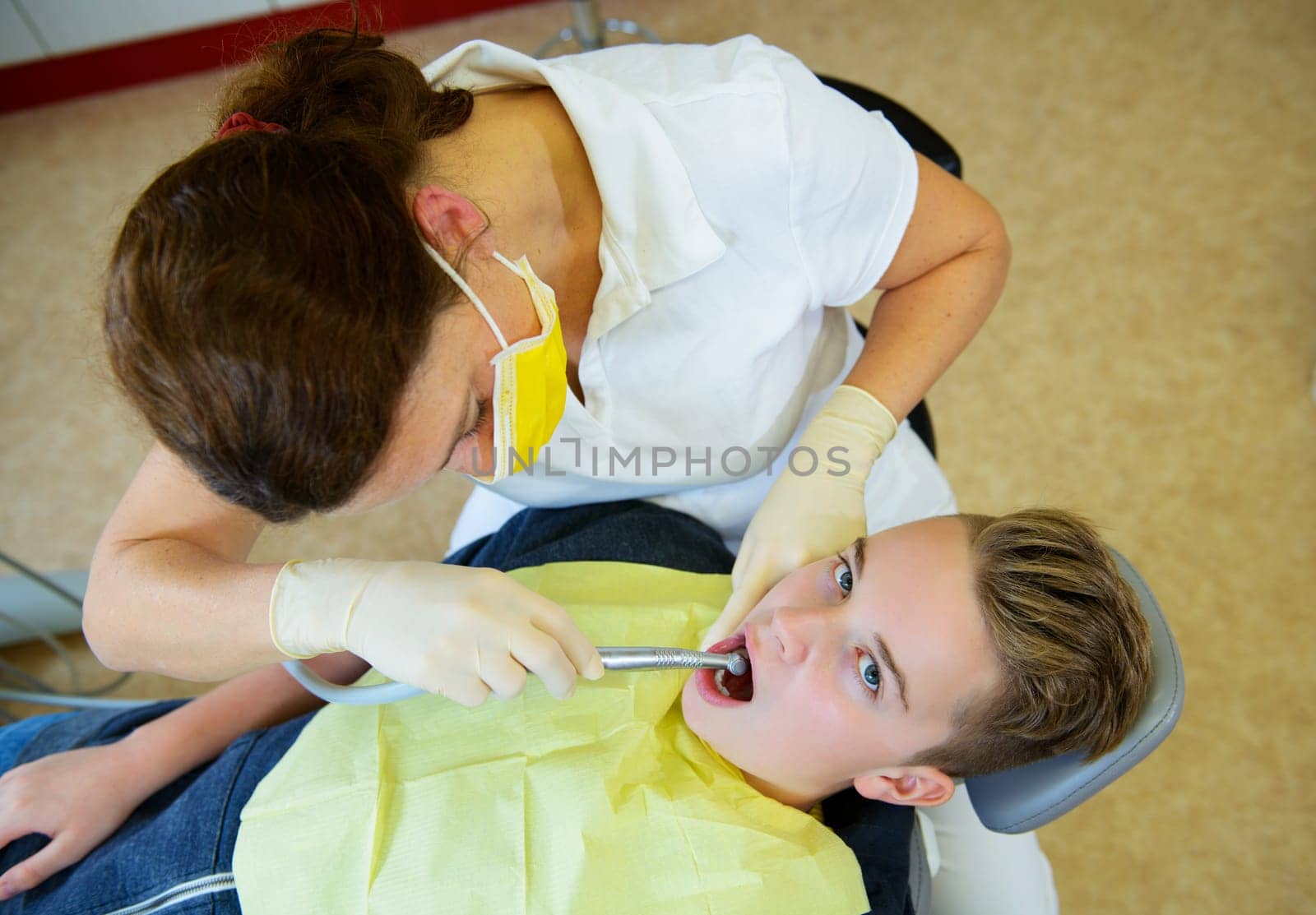 teenager is treated by female dentist in dental surgery