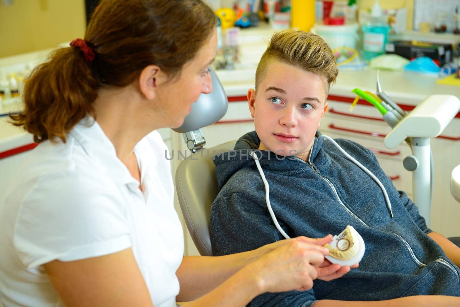 teenager is treated by female dentist in dental surgery