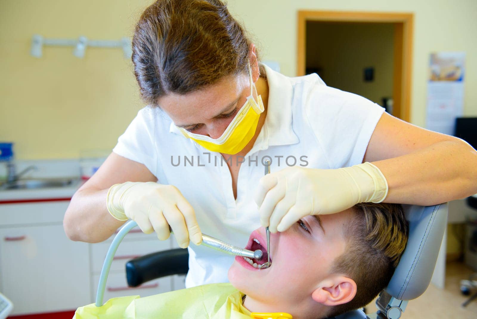 teenager is treated by female dentist in dental surgery