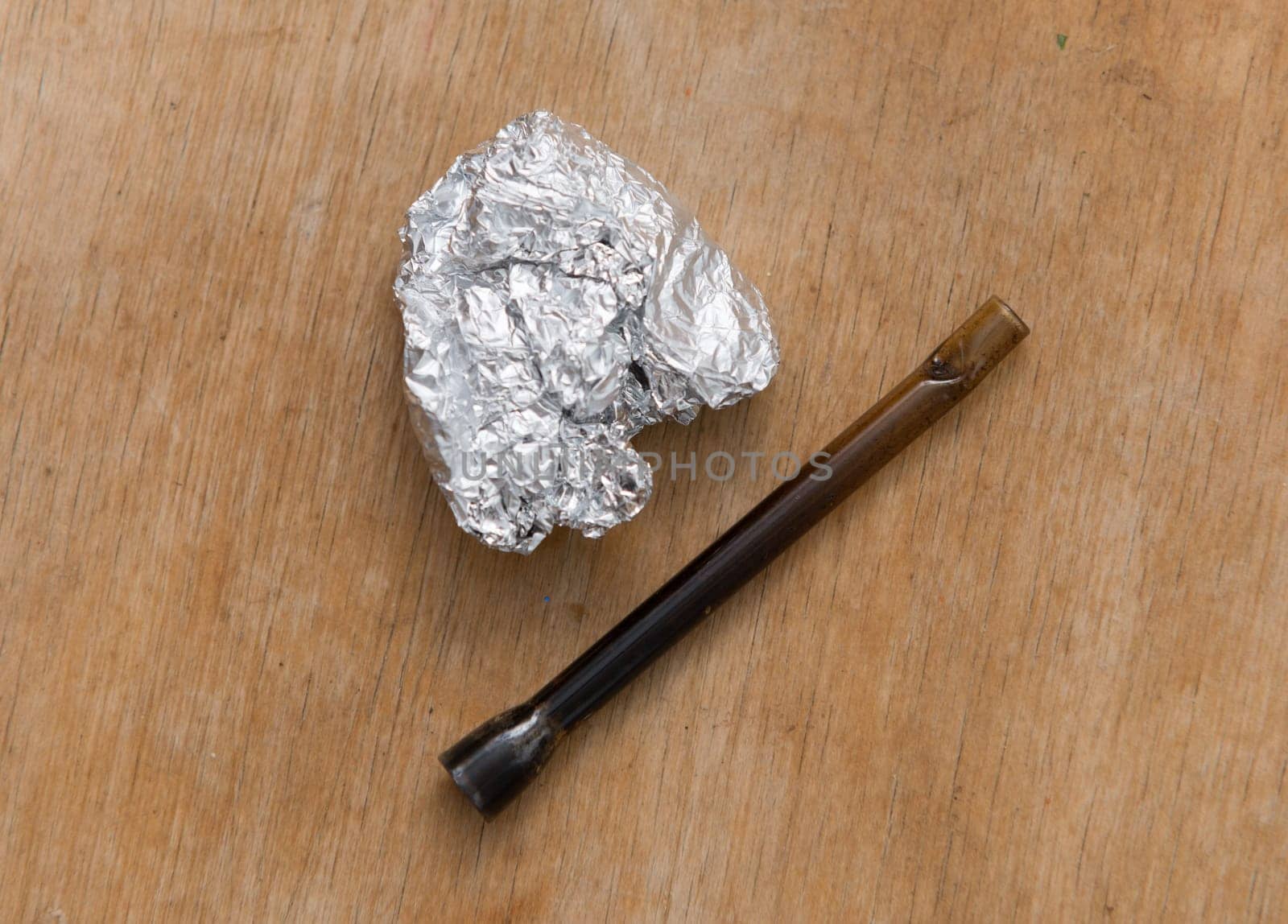 marijuana in tin foil with pipe on wooden table