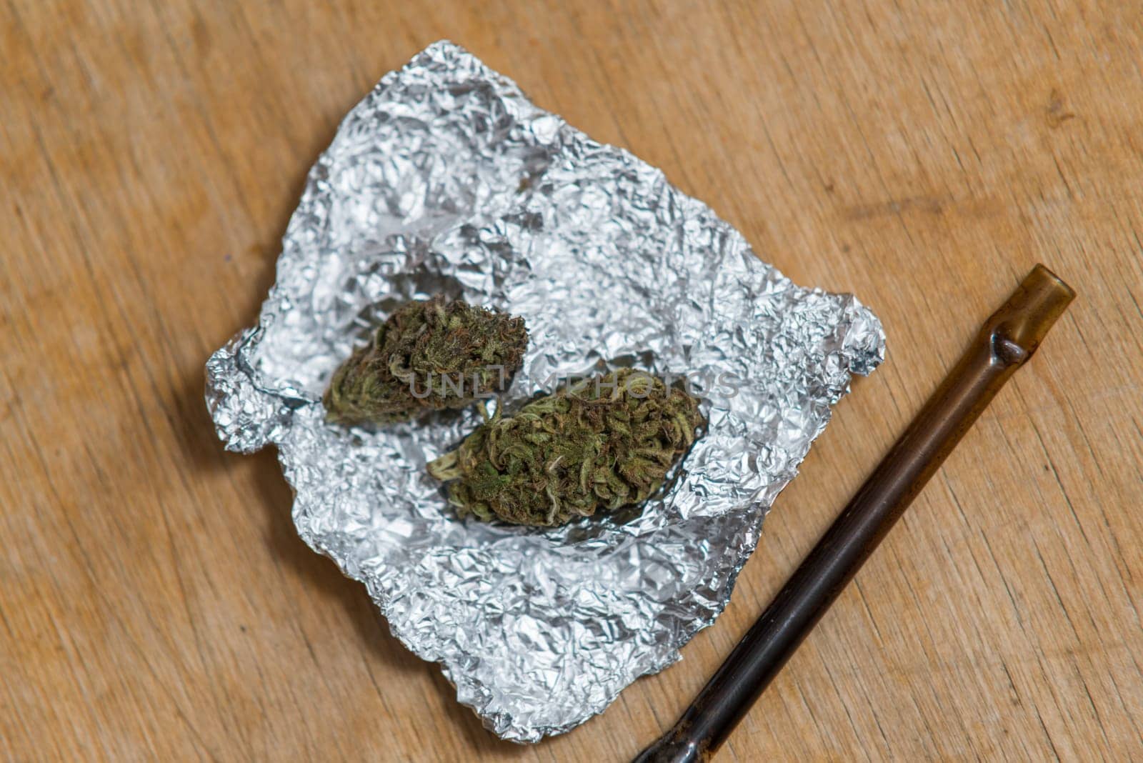 marijuana in tin foil with pipe on wooden table