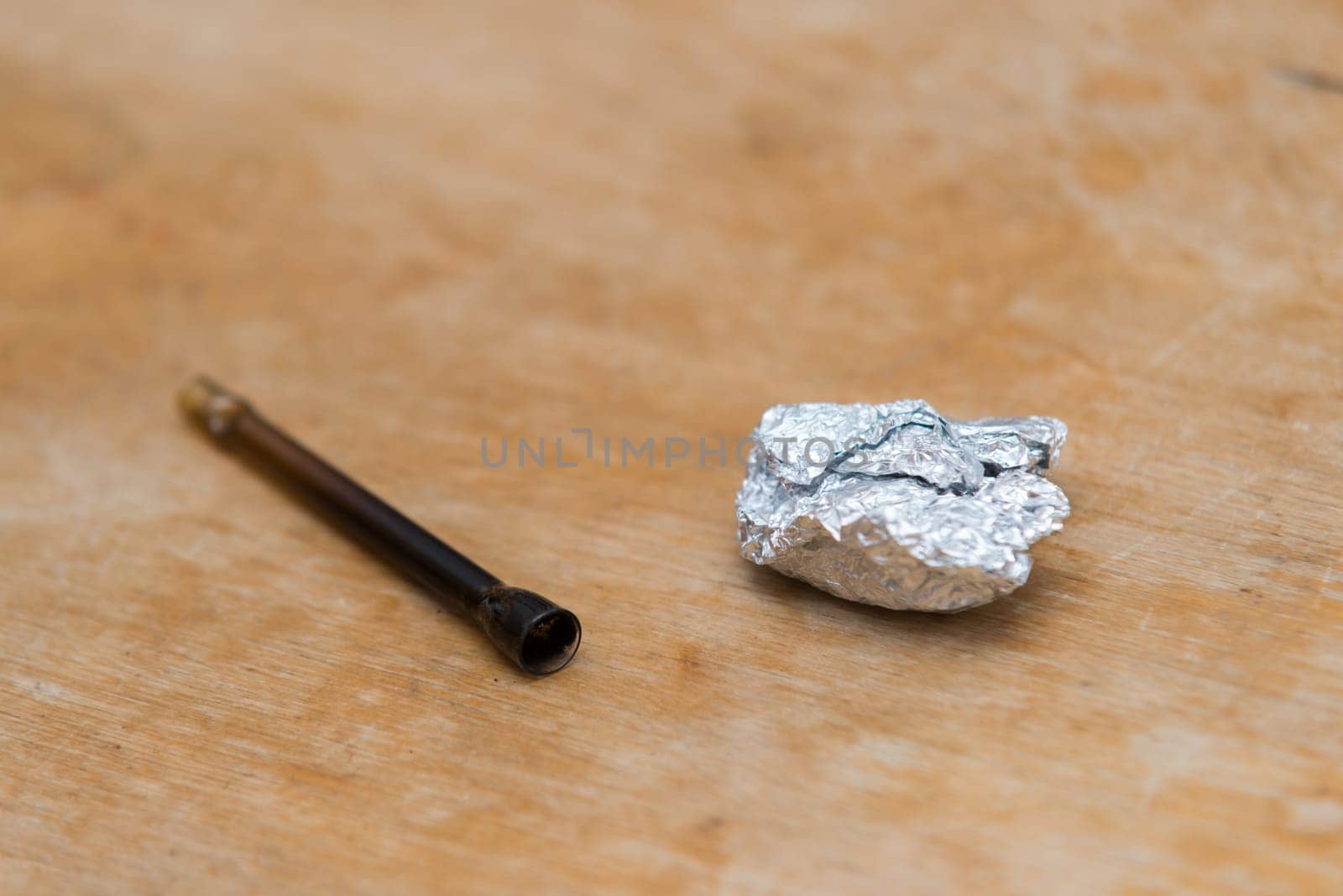 marijuana in tin foil with pipe on wooden table