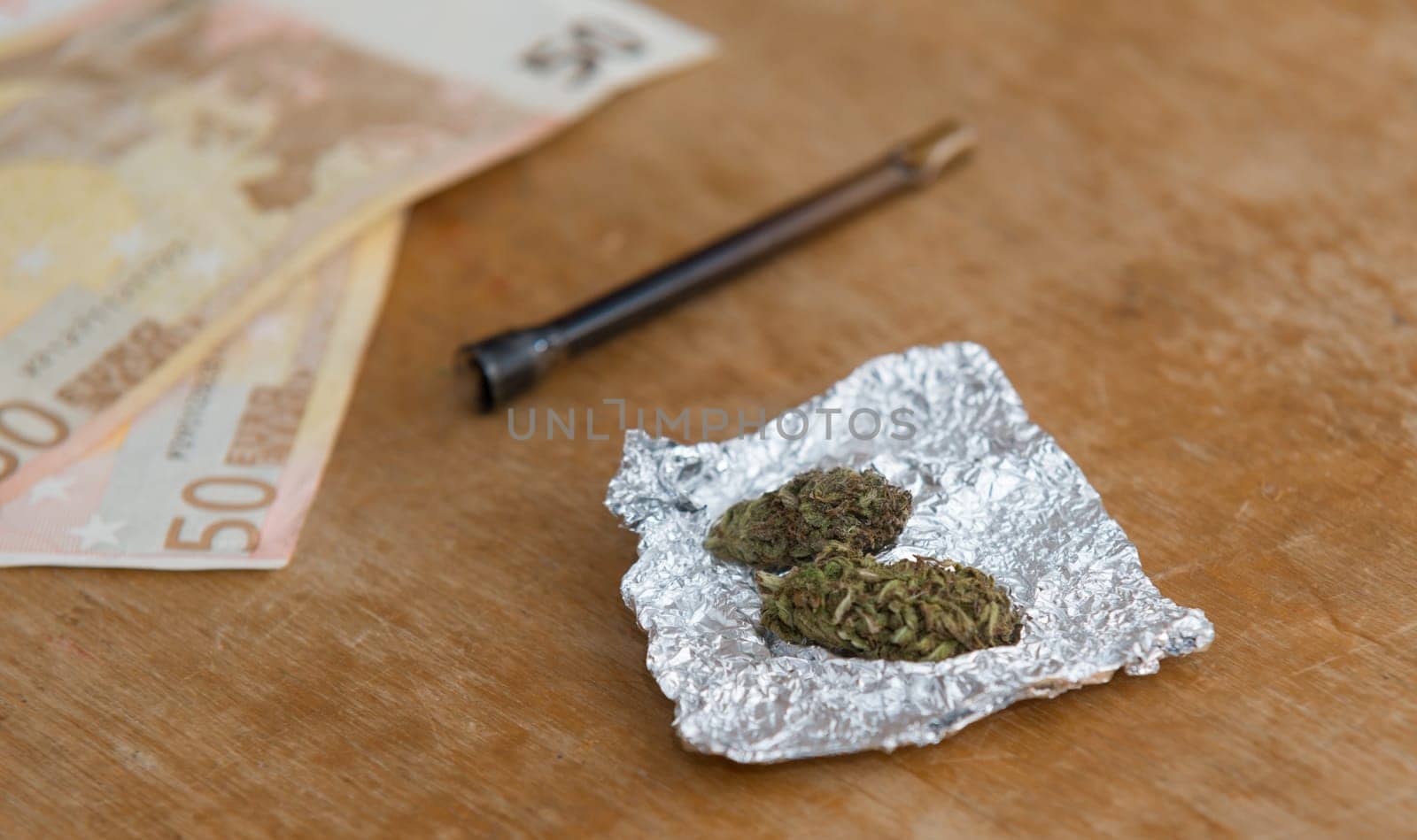 close up on marijuana in tin foil with pipe,euro money in background
