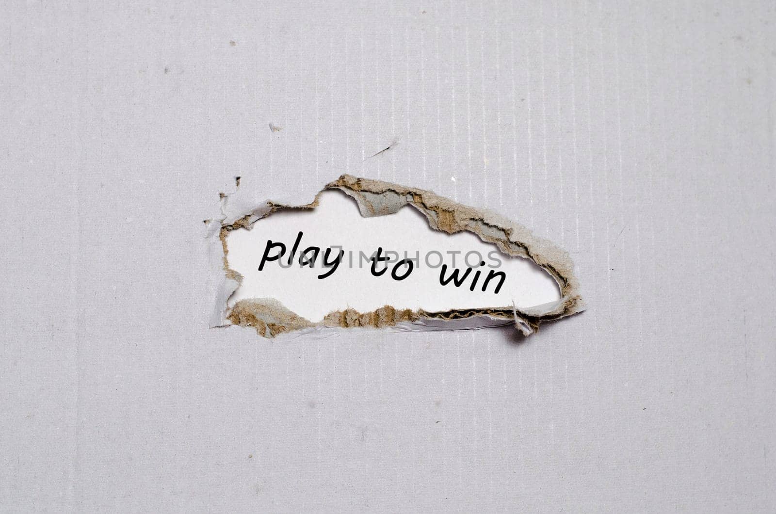 The word play to win appearing behind torn paper