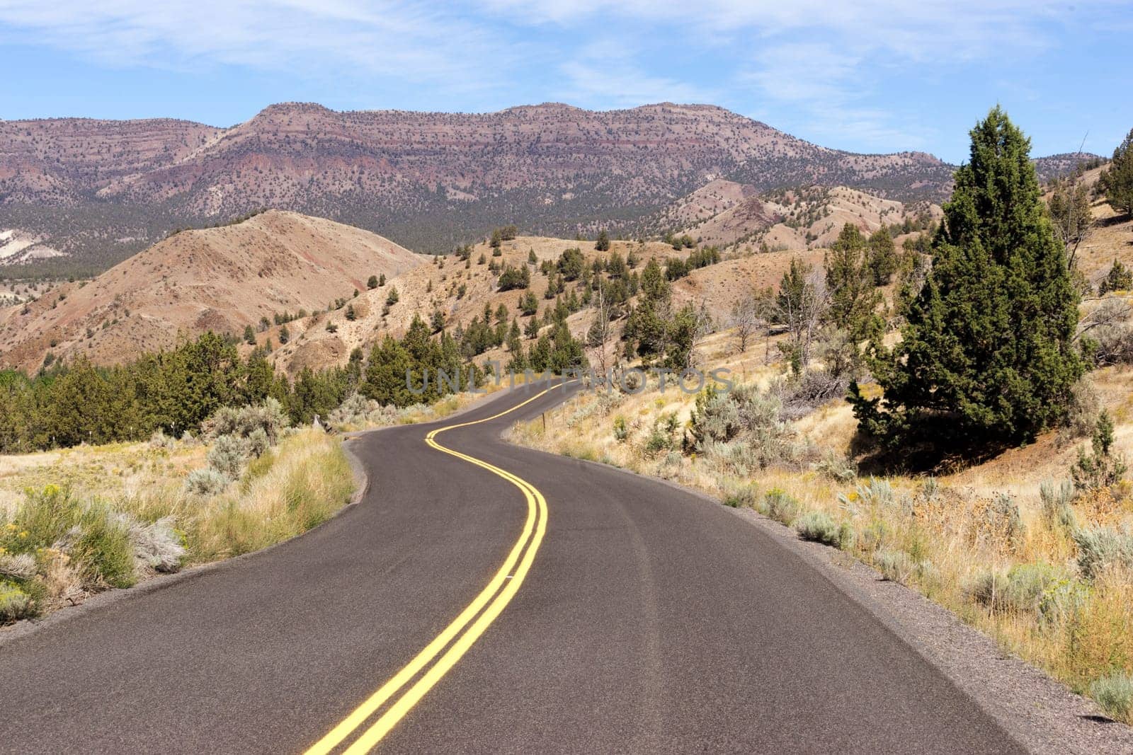 Two Lane blacktop road leads through scenic countryside