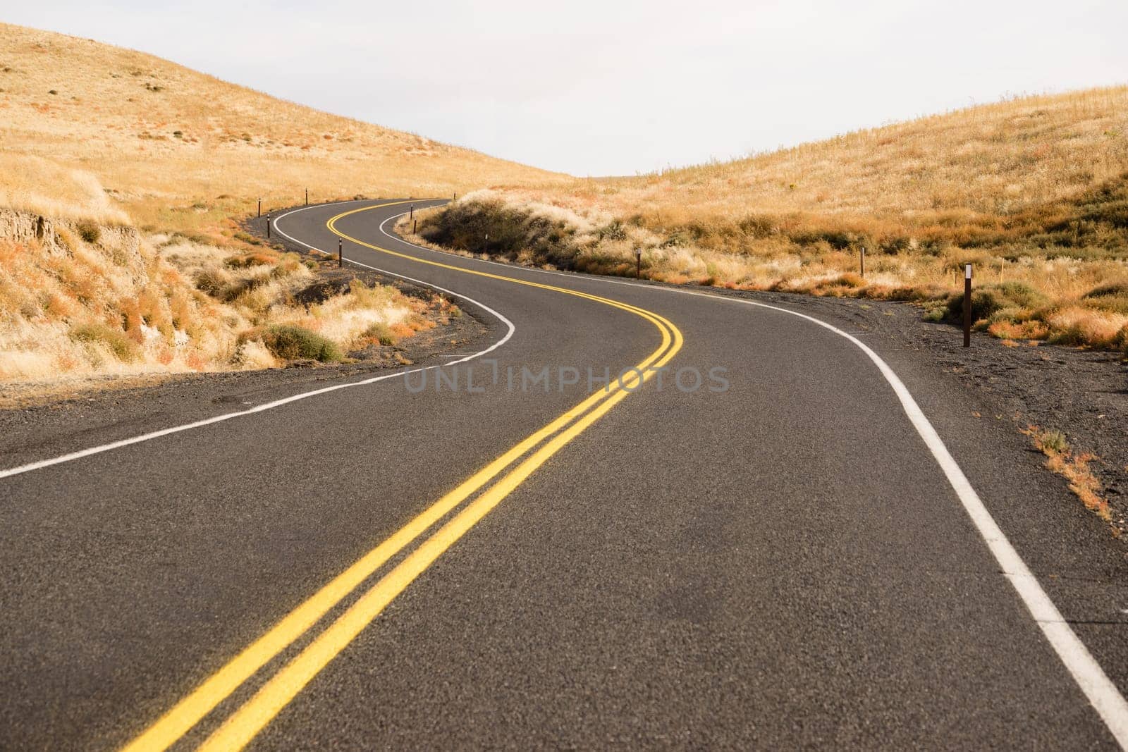 Two Lane blacktop road leads through scenic countryside
