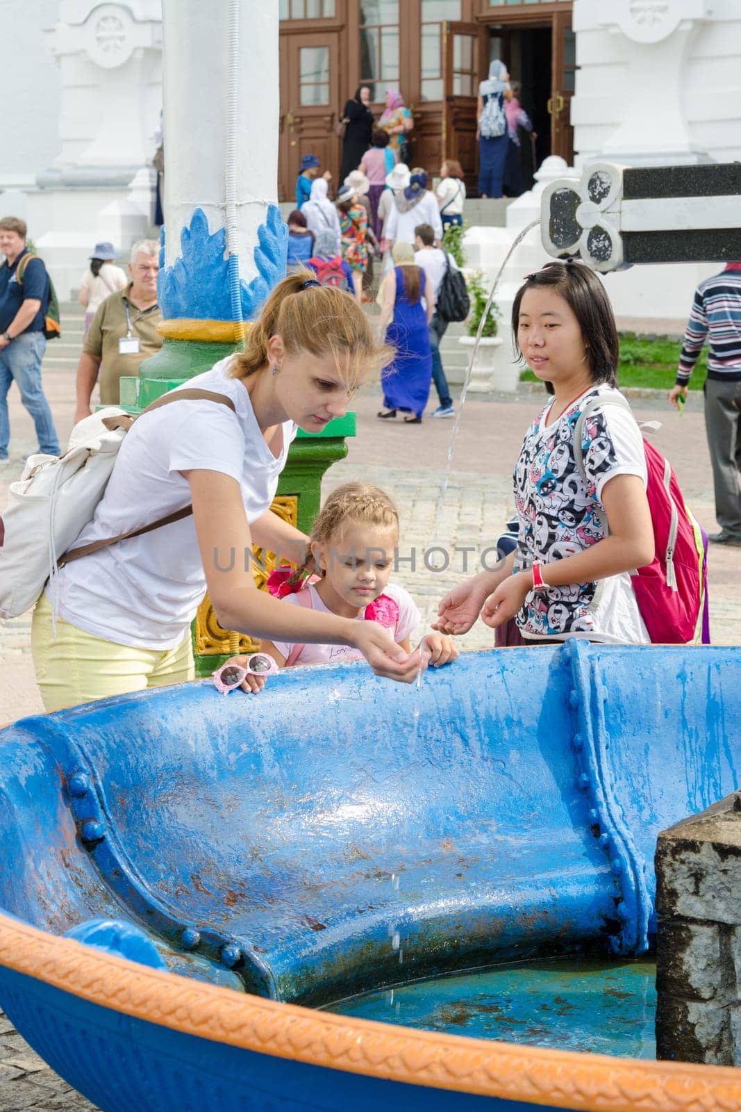 Sergiev Posad - August 10, 2015: She visitor Holy Trinity St. Sergius Lavra washes the baby's face with holy water at the canopy over the cup with a cross