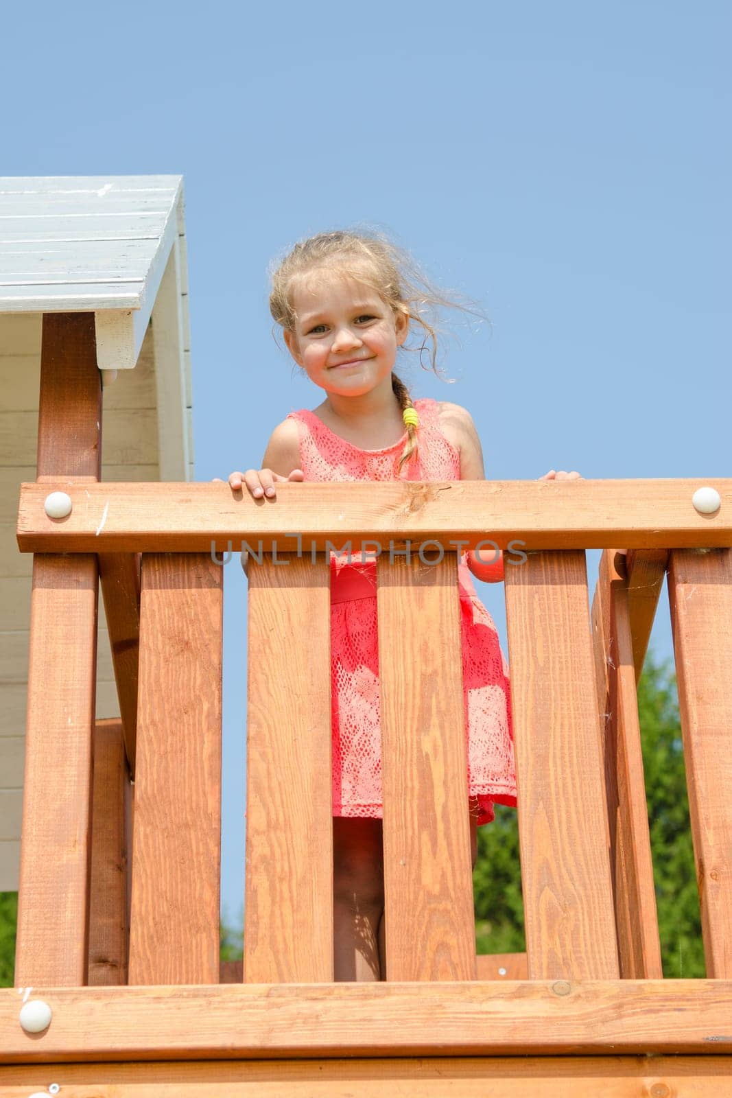 Happy little girl in a pink dress on playground