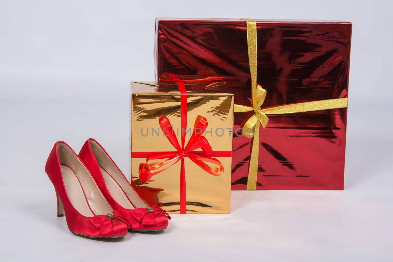 Red female shoes with high heels, standing next to two boxes with gifts