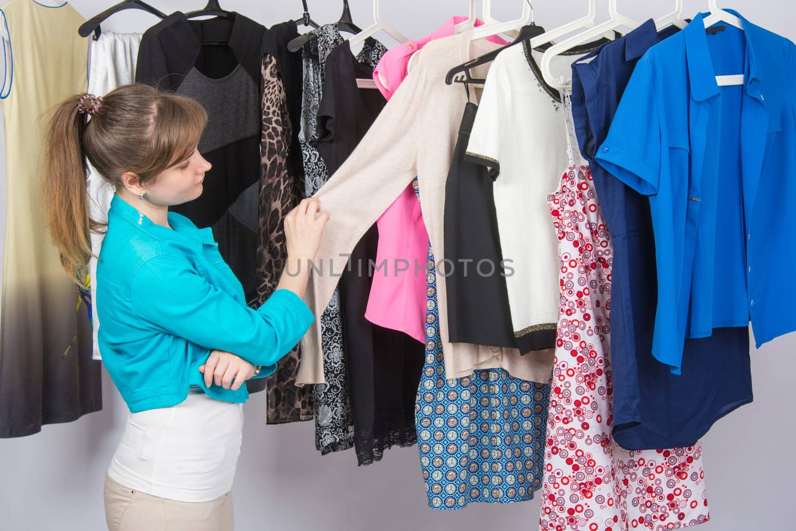 Young girl thoughtfully chooses clothes in a wardrobe